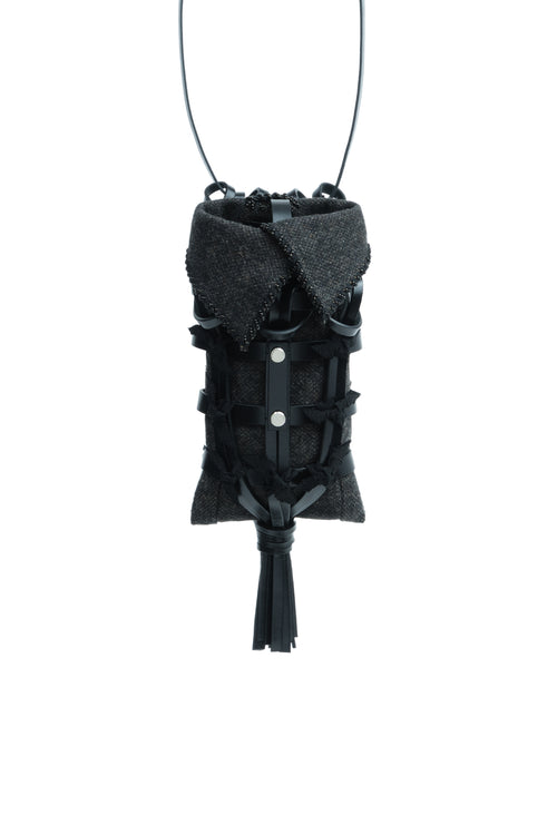 Epijé Seed Bag in Black with a textured dark gray collar, black leather straps, silver snap buttons, and a tassel, suspended on a thin black cord against a white background.