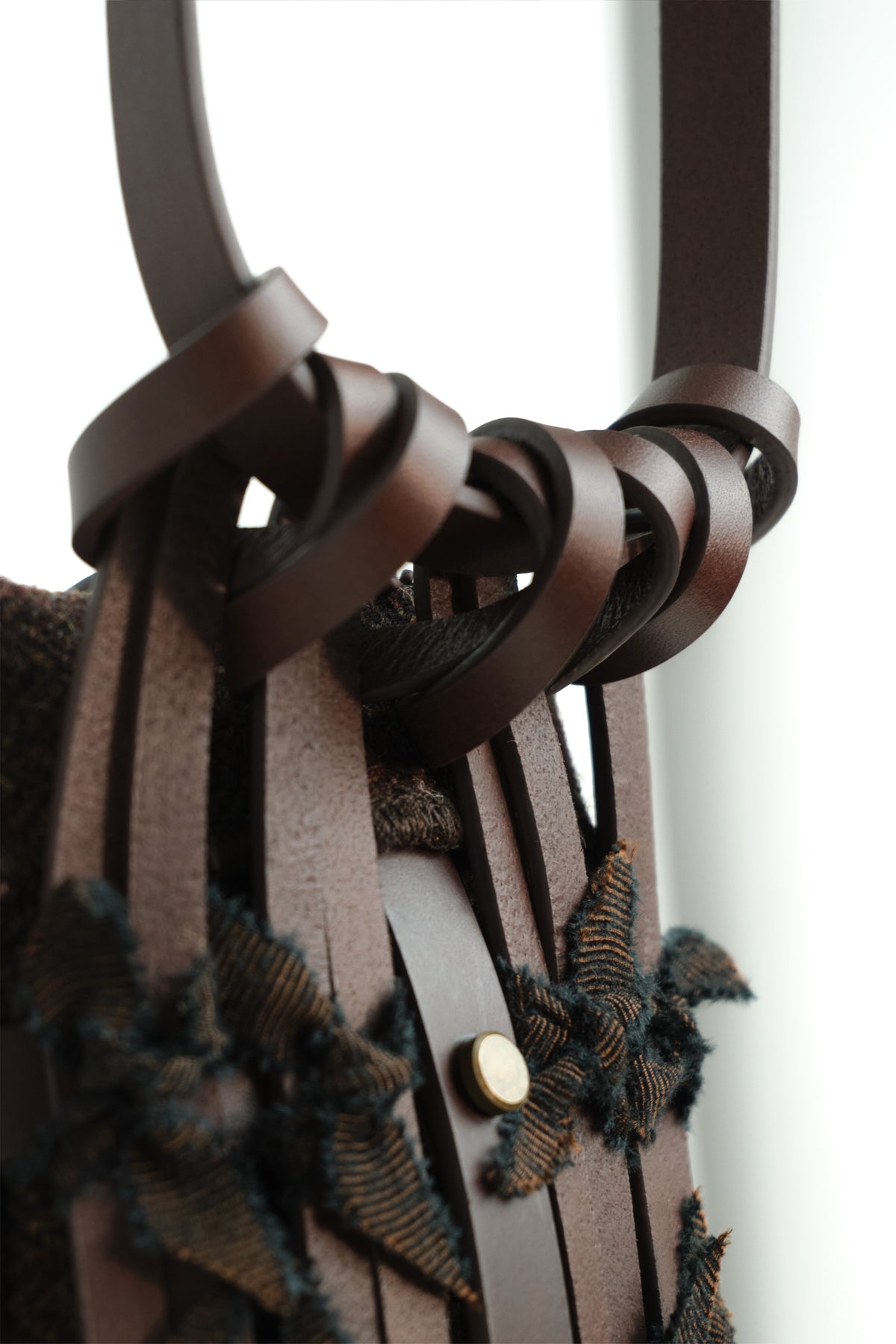 Close-up of Epijé Seed Bag in Brown  with twisted strap details and textured fringe accents, shown against a bright white background.