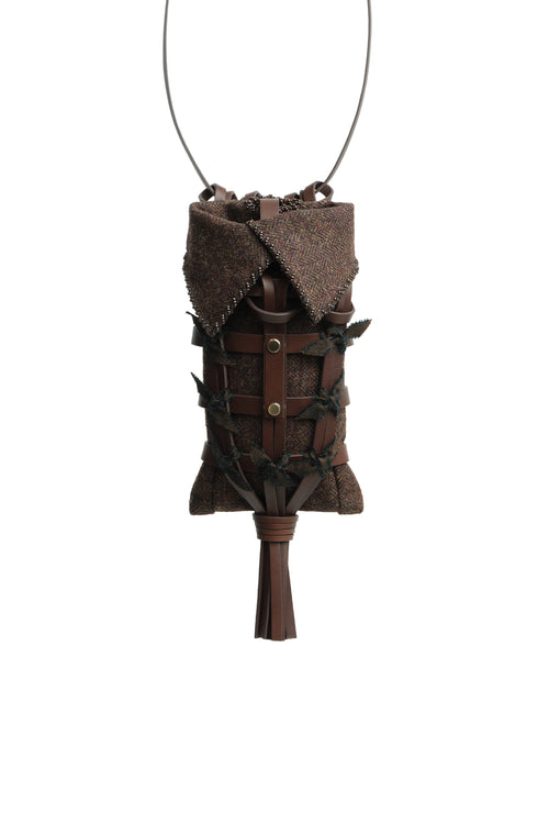 Epijé Seed Bag in Brown with a textured fabric lining, decorative stitched details, and a tassel at the bottom, suspended from a thin black cord against a white background.